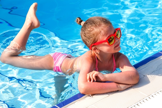 Little ballerina in the pool in summer