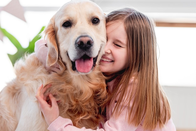 Little beautiful girl petting adorable golden retriever dog