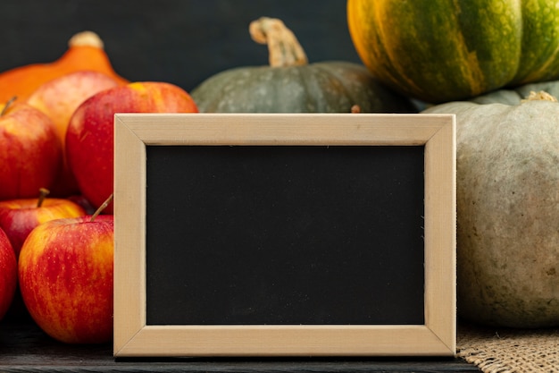 Little blackboard in wooden frame against pile of pumpkins