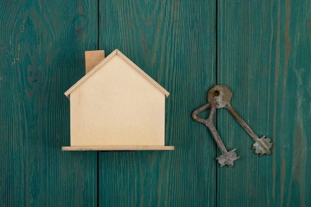 Little blank house and key on blue wooden desk