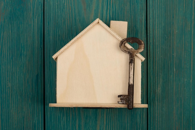 Little blank house and key on blue wooden desk