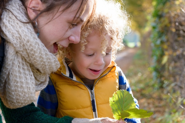 A little blond boy and his mom play outside