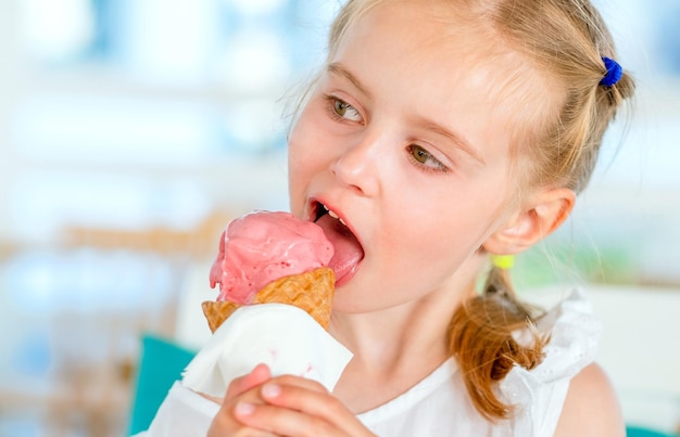 Little blond girl eating tasty pink ice cream