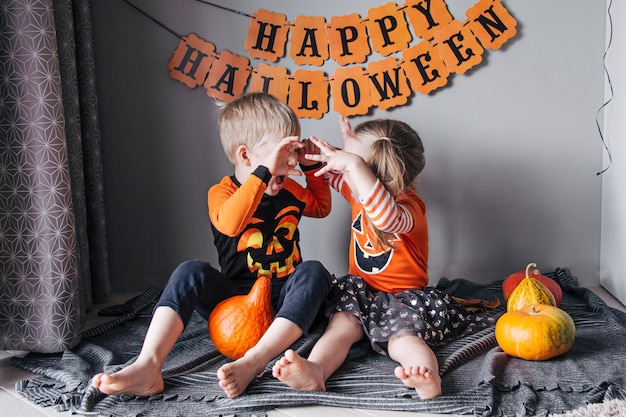 A little blonde girl and a boy in a pumpkin costume for Halloween trick or treat children celebrate Halloween Ready for the trick or treat holiday