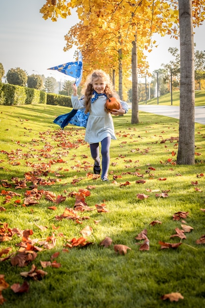 Little blonde girl dressed as a witch, wizard for halloween. hat, cloak, pumpkin, laugh, smile, autumn. selective focus.