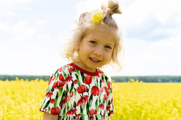 Little blonde girl in a field of rape, happy baby in a field of flowers.