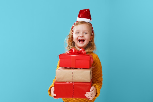 Little blonde girl holding three boxes with gifts.