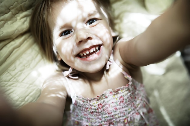 Little blonde girl lies on the bed Emotional child infant posing