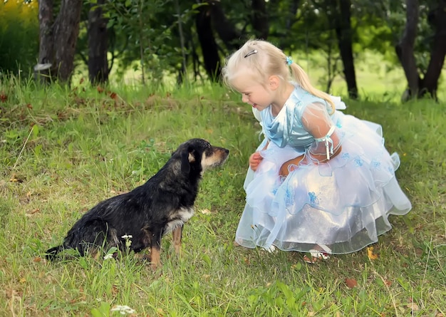 A little blonde girl with a dog in the summer garden