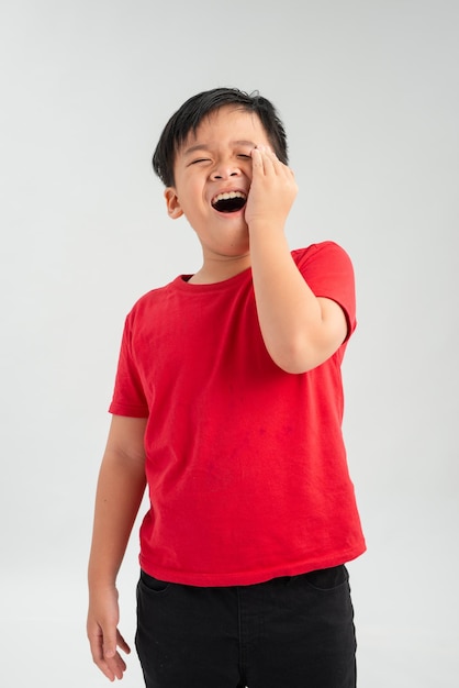 Little boy asian appearance hand to her cheek wrinkled face on a white background toothache retro