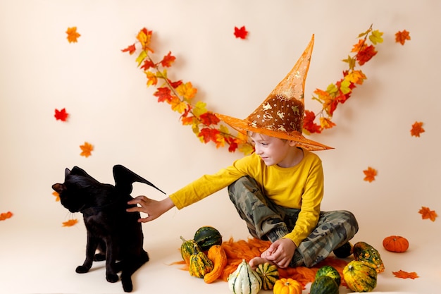 Little boy and black cat with pumpkin lantern. Halloween.