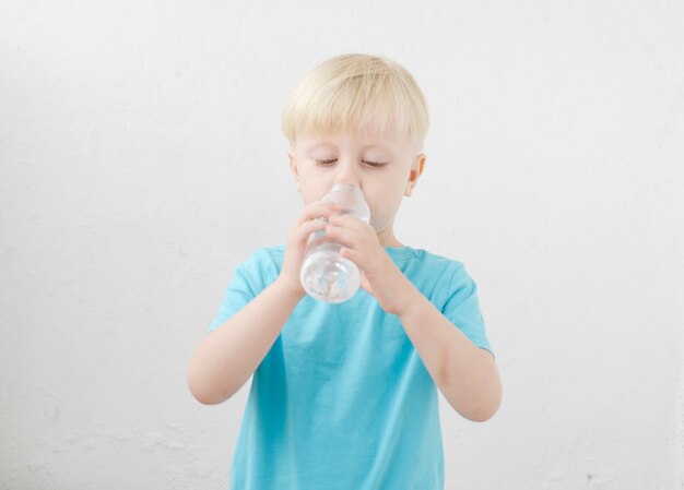 little boy in a blue Tshirt drinks water