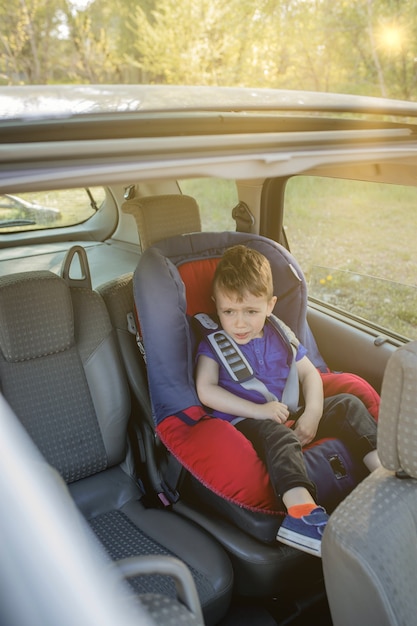 Little boy buckled up seatbelt inside the car. Vehicle and transportation concept