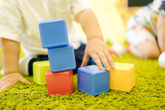 Little boy builds a tower of cubes kindergarten