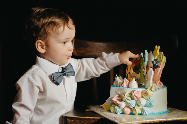 A little boy next to a cake for his birthday