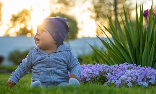 Photo little boy in a cap is sitting on the lawn