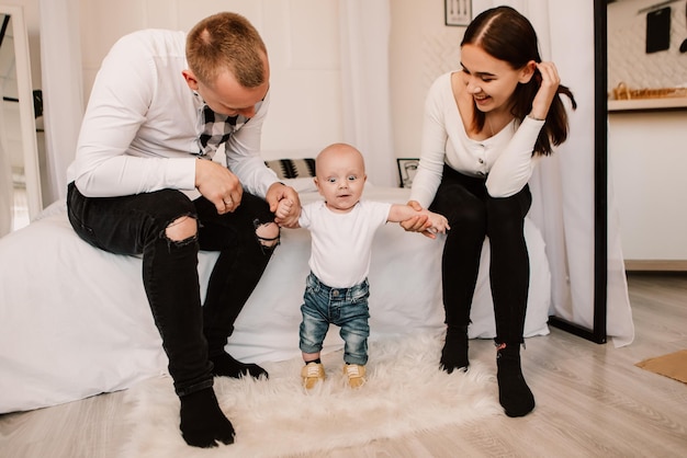 Little boy child baby playing with parents, standing learning to walk, taking first steps