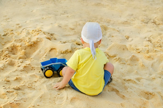 A little boy child playing in the sandbox in the summer view from the back Childhood Concept