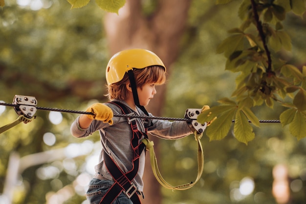 little boy climbing in the trees with helmet and protection gloves