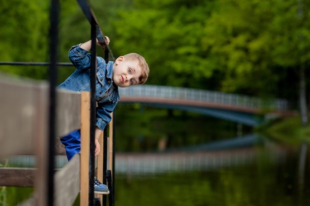 A little boy climbs a bridge railing in the park The threat of drowning Danger to children