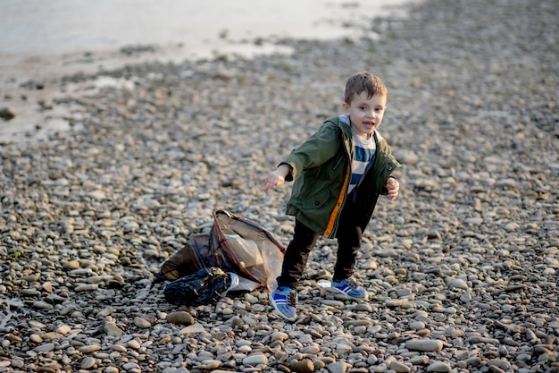 little boy collecting garbage and plastic bottles on the beach to dumped into the trash