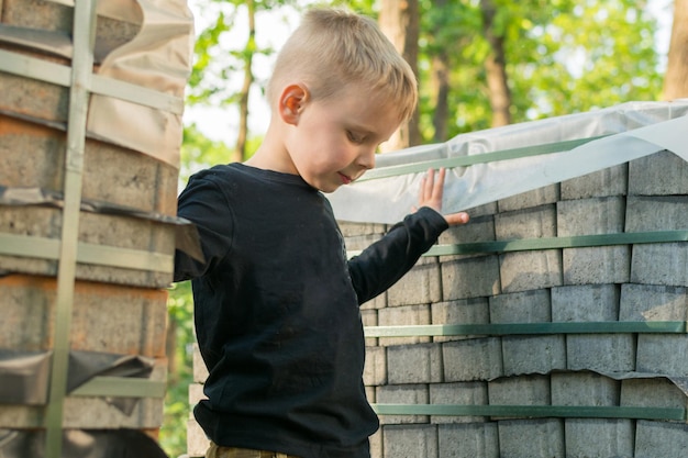 A little boy on a construction site near stacks with paving tiles