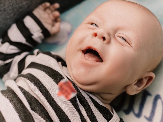 Little boy cute child lying in baby carriage pram buggy having fun smiling laughing, playing