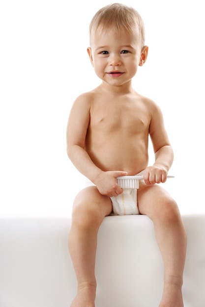 Little boy in diaper sitting and playing with brush