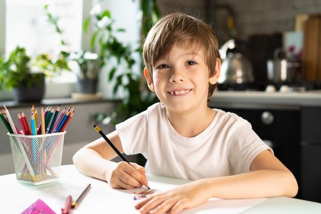 The little boy doing lessons at home at the table, distance learning online education.