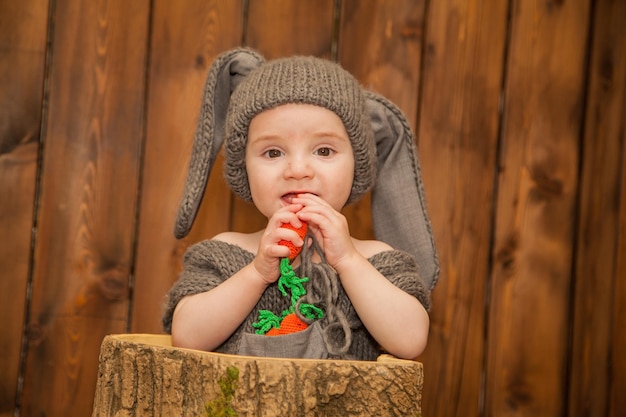 A little boy dressed as a bunny nibbles on a carrot halloween baby costume