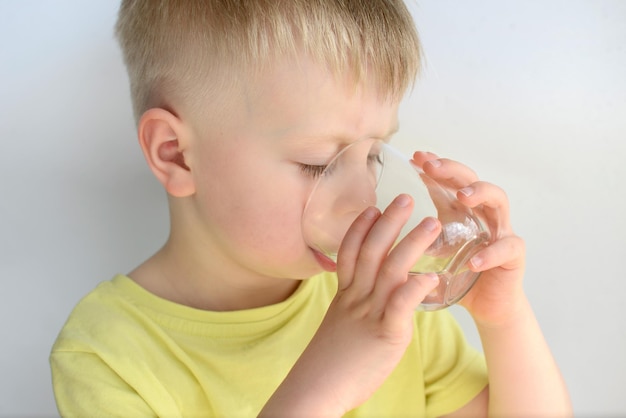 little boy drinks water from a glass