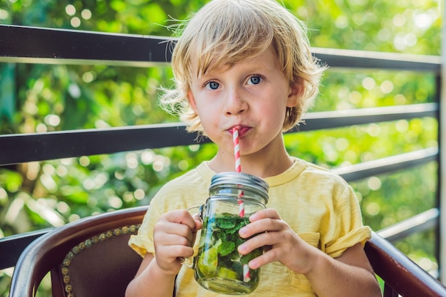 A little boy drinks water with mint and lime drink more water concept