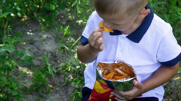 Little boy eats potato chips from a pack