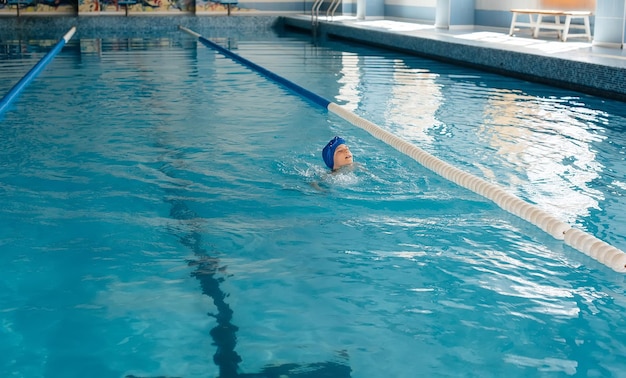 A little boy of eight years old is learning to swim in a modern swimming pool Development of children's sports Healthy parenting and promotion of children's sports