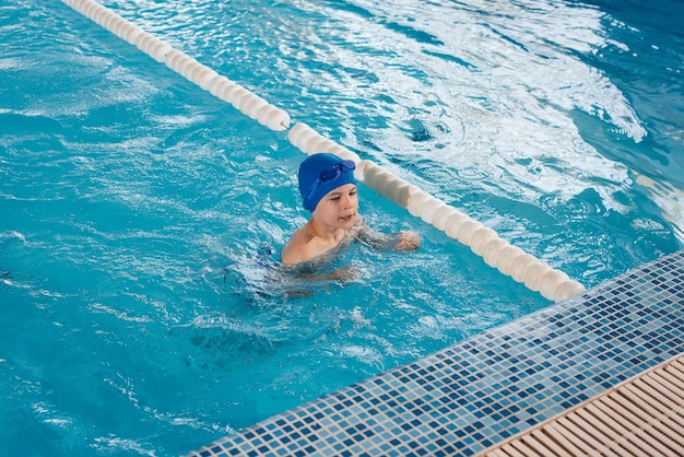 A little boy of eight years old is learning to swim in a modern swimming pool Development of children's sports Healthy parenting and promotion of children's sports