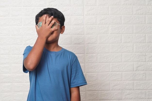 Little boy forgetting something, slapping forehead with palm and closing eyes.