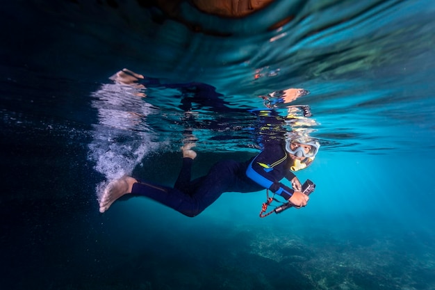 Little boy free diving in an open cave