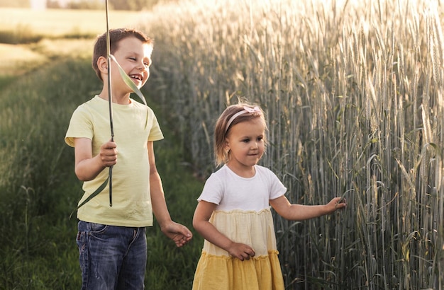 Little boy and girl play in field kids in summer meadow Family vacation in the country Siblings love