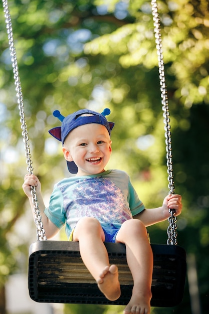 Little boy having fun on chain swing on the playground