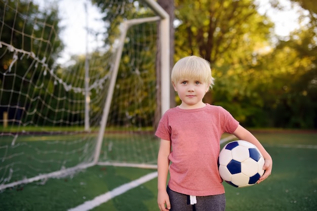 Little boy having fun playing a soccer/football game on summer day. 