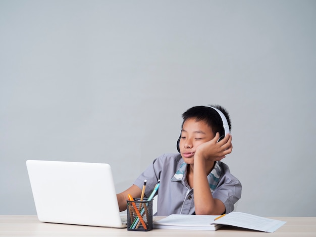 Little boy in headphones studying online using laptop