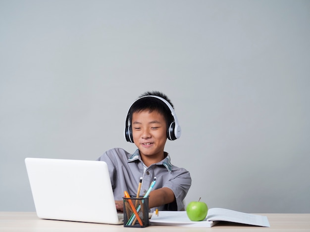 Little boy in headphones studying online using laptop