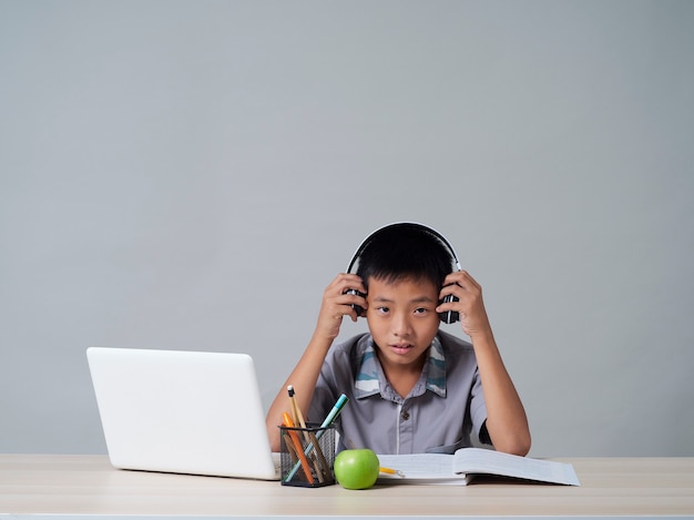 Little boy in headphones studying online using laptop