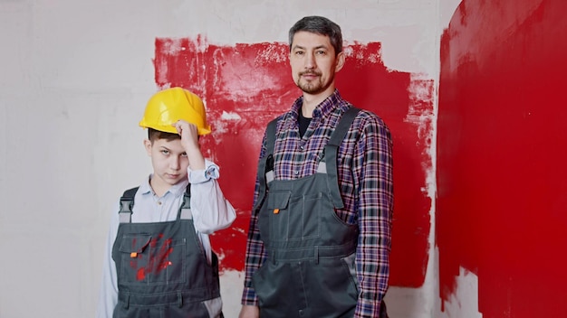 A little boy and his father painting walls  a boy puts on a helmet and holding a roller