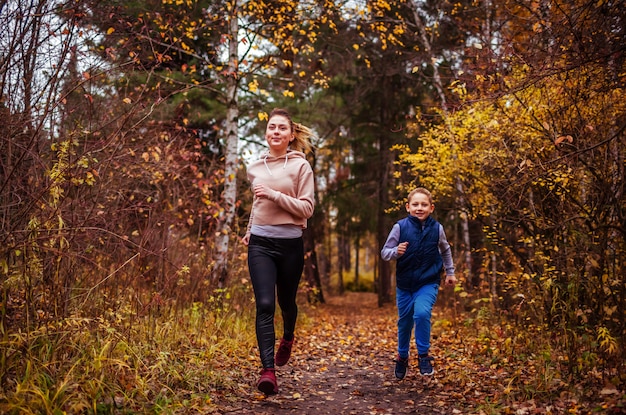 Little boy and his sister running in autumn forest