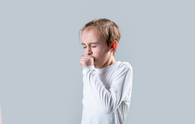 Little boy is coughing on gray background Boy coughing sick colds sneezing cough Child got sick with a virus Children coughs Child is ill he coughs Treatment of colds and flu Covid19