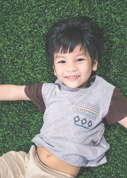 Little boy is lying down on soccer field top view