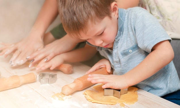 A little boy is making a star out of dough