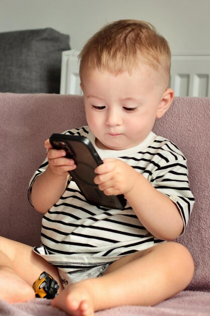 Photo a little boy is playing a game with a phone