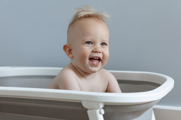 Little boy is sitting in a bath and laughing